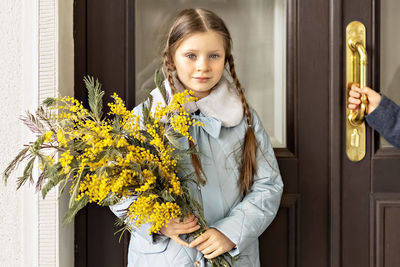 A  girl  in spring coats with a bouquet of acacia