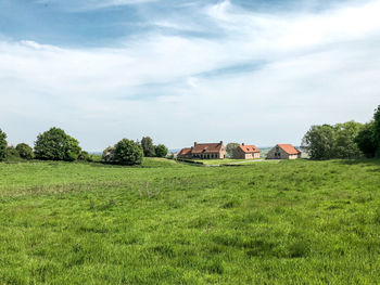 Houses and trees on field against sky