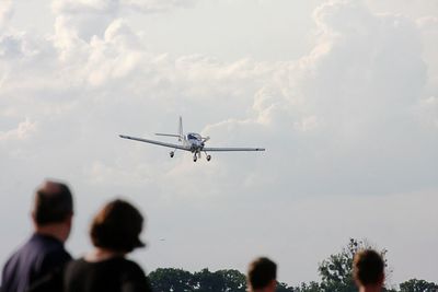 Low angle view of people at airplane against sky