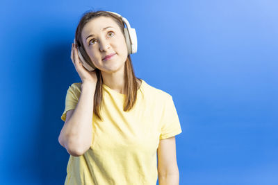 Portrait of smiling young woman against blue wall
