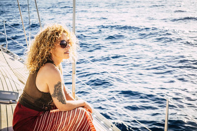 Side view of woman sitting on sailboat in sea