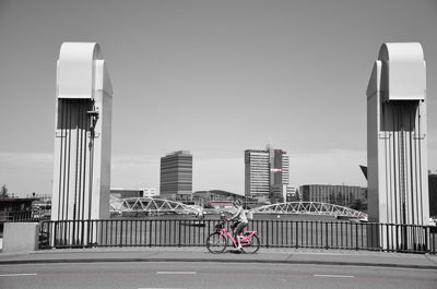 Man riding bicycle on road against buildings in city