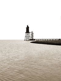 Rear view of silhouette man standing by sea against clear sky