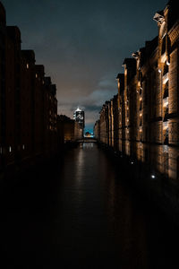 Canal amidst illuminated buildings in city at night