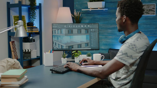 Rear view of woman using laptop at office