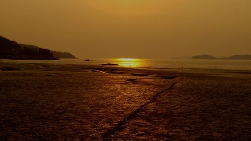 Scenic view of beach against clear sky during sunset