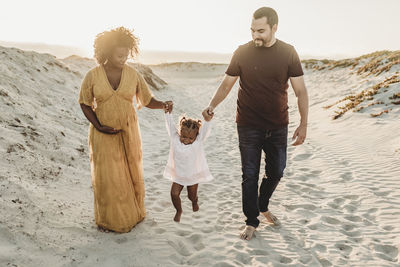 Young family of three walking and playing at beach