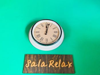 Close-up of wall clock and text on blue background