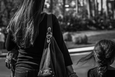 Rear view of mother and daughter walking on road