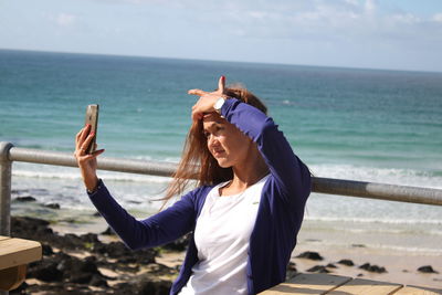 Woman taking selfie at beach on sunny day