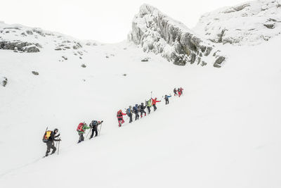 Low angle view of hikers climbing snow covered mountain