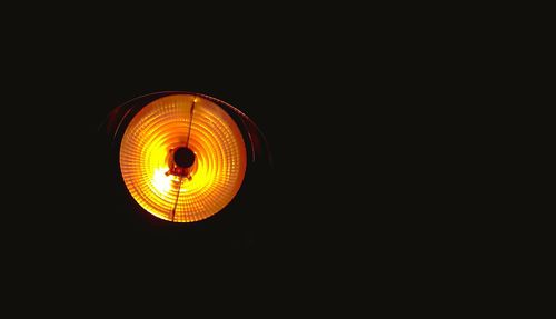 Low angle view of illuminated lamp against black background