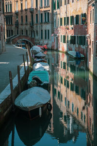 Boats moored in canal amidst buildings in city