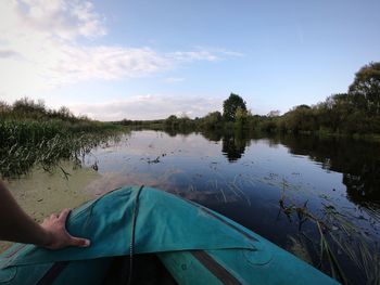 Low section of person by lake against sky