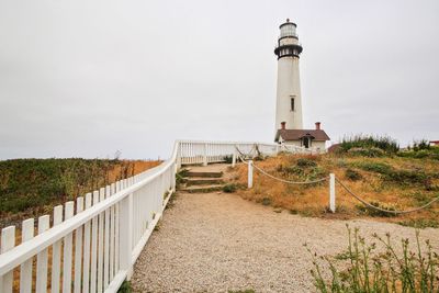 Lighthouse by sea against clear sky