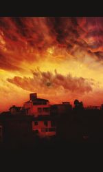 Silhouette of building against cloudy sky at sunset