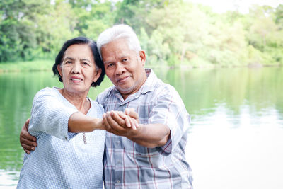 Portrait of couple holding hands by lake