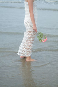 Low section of woman standing on beach