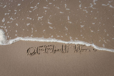 High angle view of text offline on sand at beach
