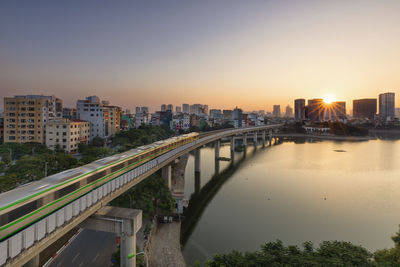 The train is running across the lake in the sunset