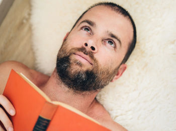 Portrait of man lying down reading a book