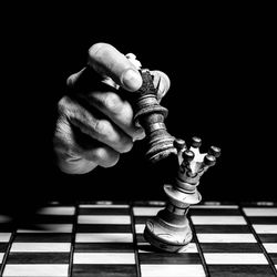 Low angle view of man playing chess against black background