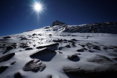 Scenic view of snow covered mountains against bright sun