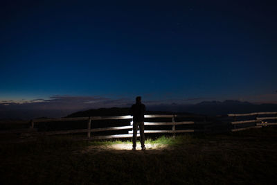 Rear view of silhouette man standing on field against sky