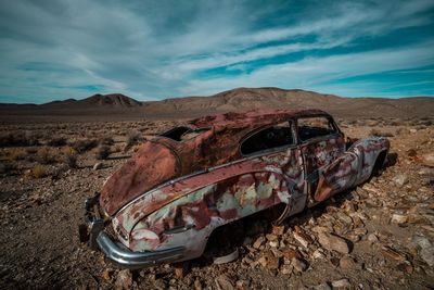 Abandoned truck on land against sky