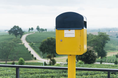 Close-up of yellow mailbox against trees and sky