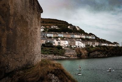 Buildings by sea against sky