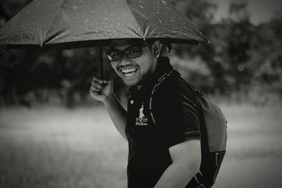 Portrait of happy man holding umbrella