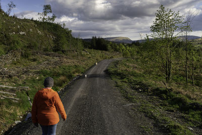 Rear view of man standing on road against sky