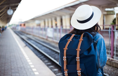 Rear view of woman with backpack standing on railroad station