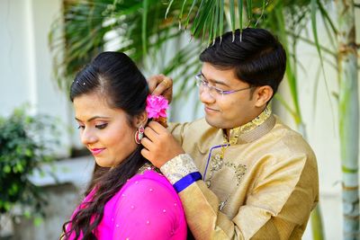 Romantic groom putting flower on bride hair in park