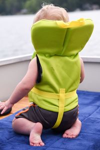Rear view of girl sitting on yellow leaf