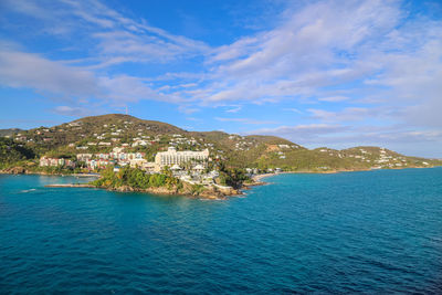 Scenic view of sea by townscape against sky