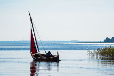 Man in sailboat on sea against sky