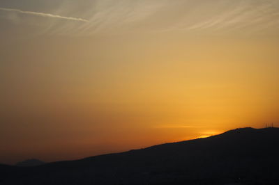 Scenic view of silhouette mountains against orange sky
