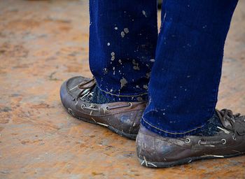 Low section of man wearing dirty shoes on wooden floor