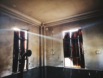 Low angle view of illuminated lamp on wall in building