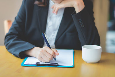 Midsection of man using mobile phone on table