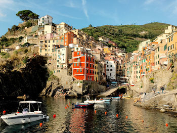 Sailboats moored on sea by buildings in city against sky