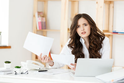 Portrait of young businesswoman holding document at office