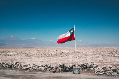 Flag on landscape against clear blue sky