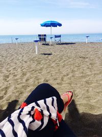 Deck chairs on sand at beach against sky