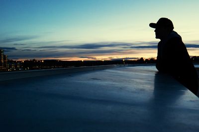 Side view of silhouette man sitting on road at sunset
