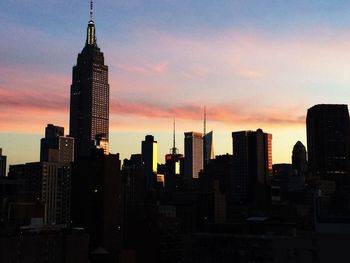 Skyscrapers in city at sunset