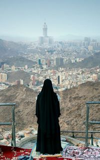 Rear view of woman wearing black dress while standing against cityscape