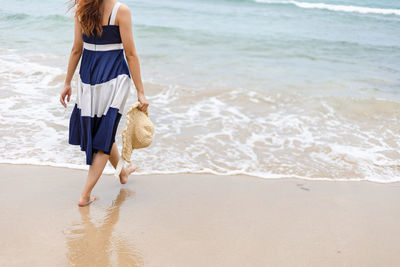 Low section of woman walking at shore